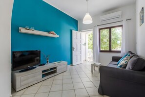 Un salon avec un téléviseur, un canapé gris, un meuble blanc et un mur bleu.