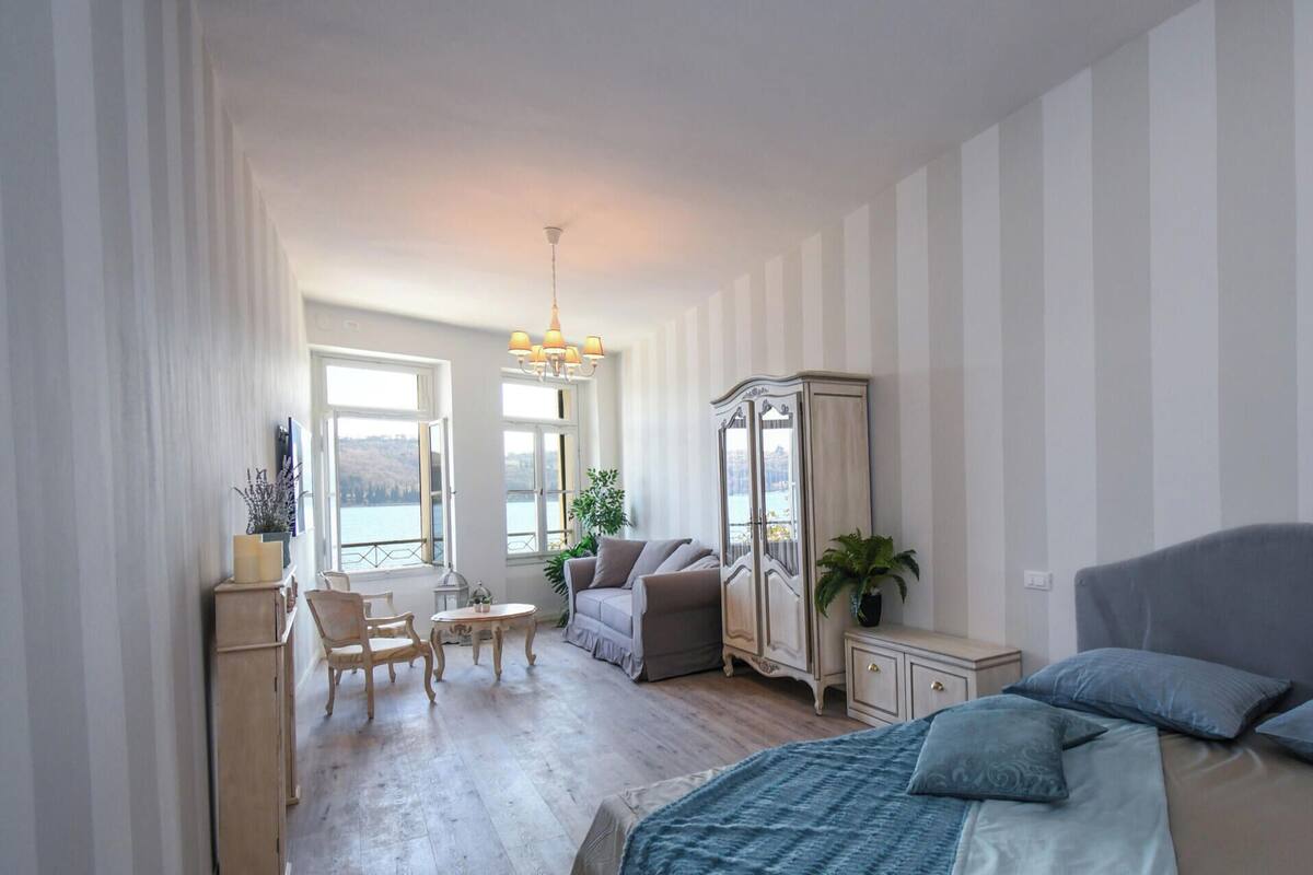 A bedroom with a bed, a desk, a chair, a wardrobe, and a view of the outdoors.