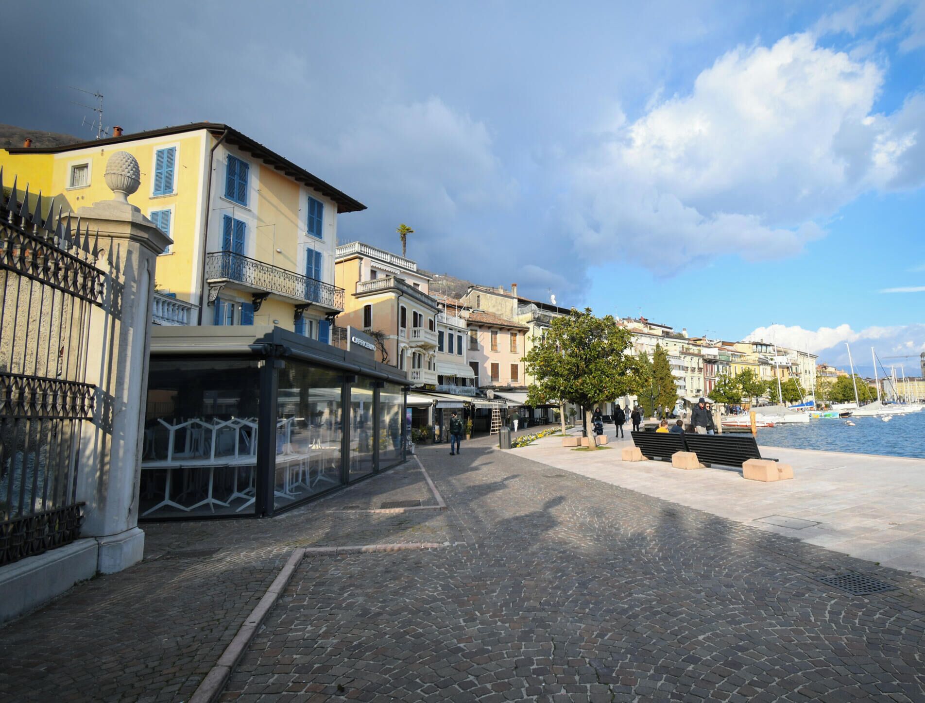 A cobblestone street with buildings, a bench, and a clear sky.