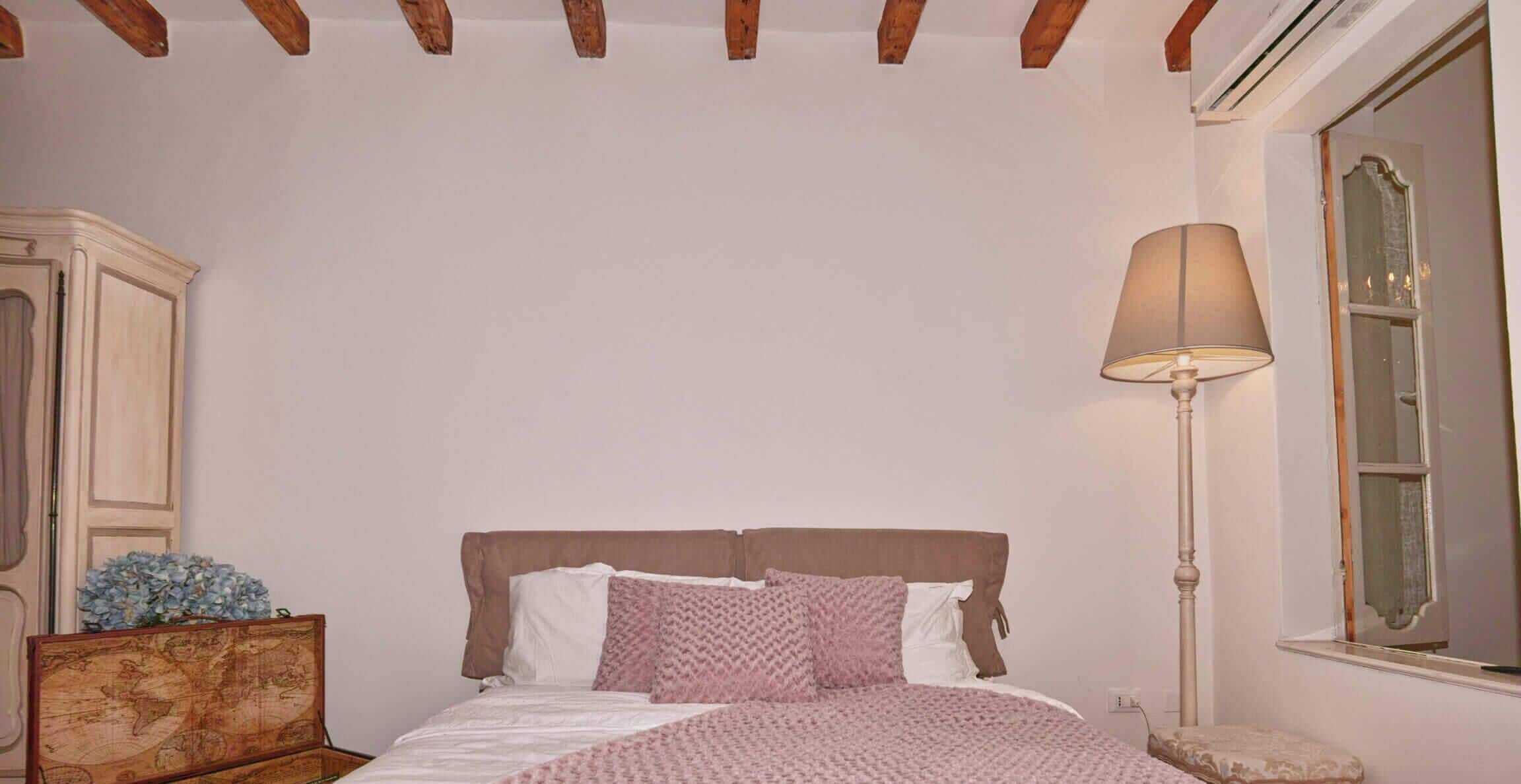 Une chambre à coucher avec un lit, une lampe, une commode et une fenêtre.