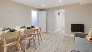 A dining area with a table set for four, a grey sofa, and a television in the living room.