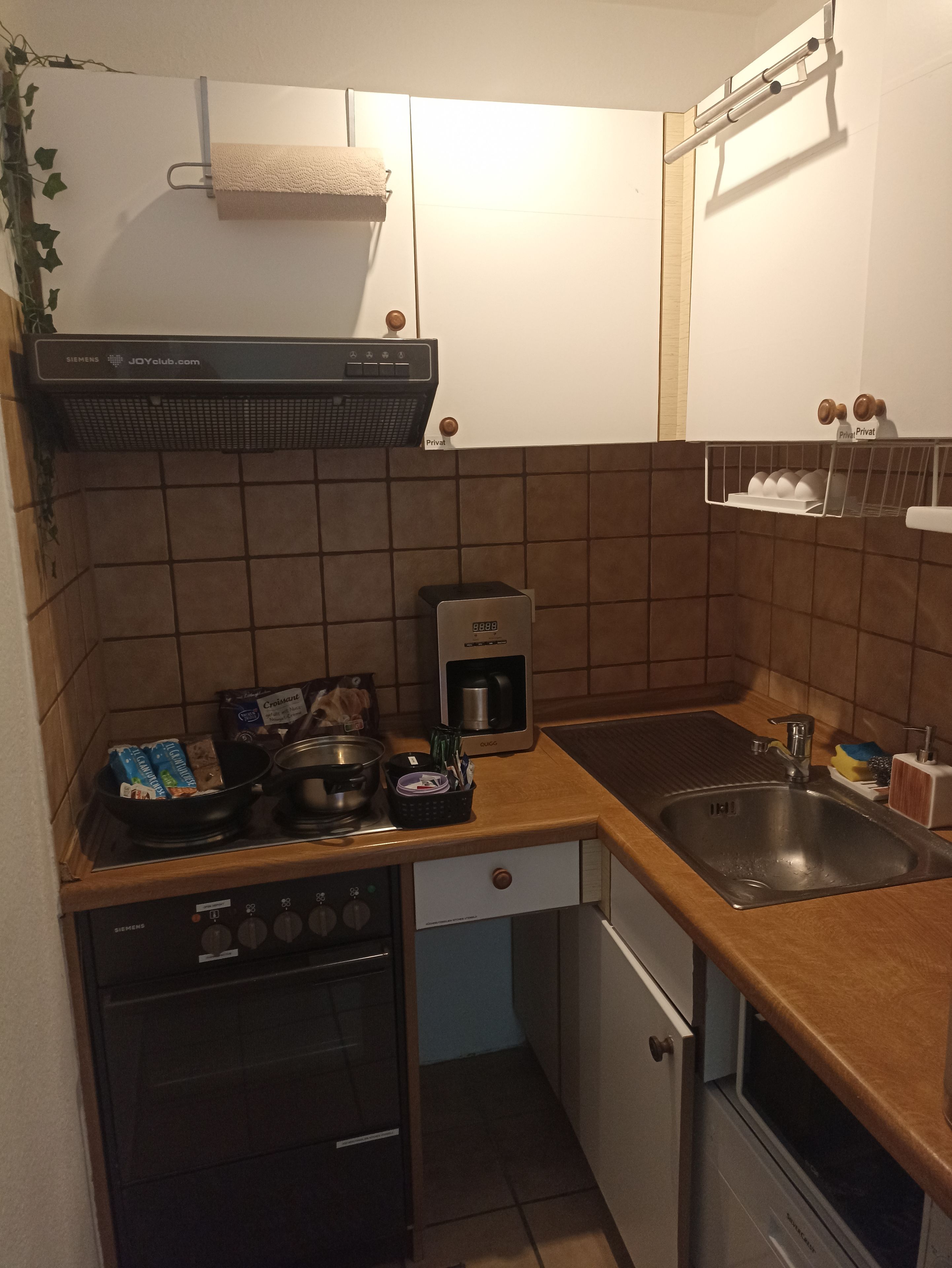 Eine kleine Küche mit einem Siemens Herd, einer Kaffeemaschine und einem Spülbecken.
