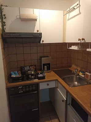 Eine kleine Küche mit einem Siemens Herd, einer Kaffeemaschine und einem Spülbecken.
