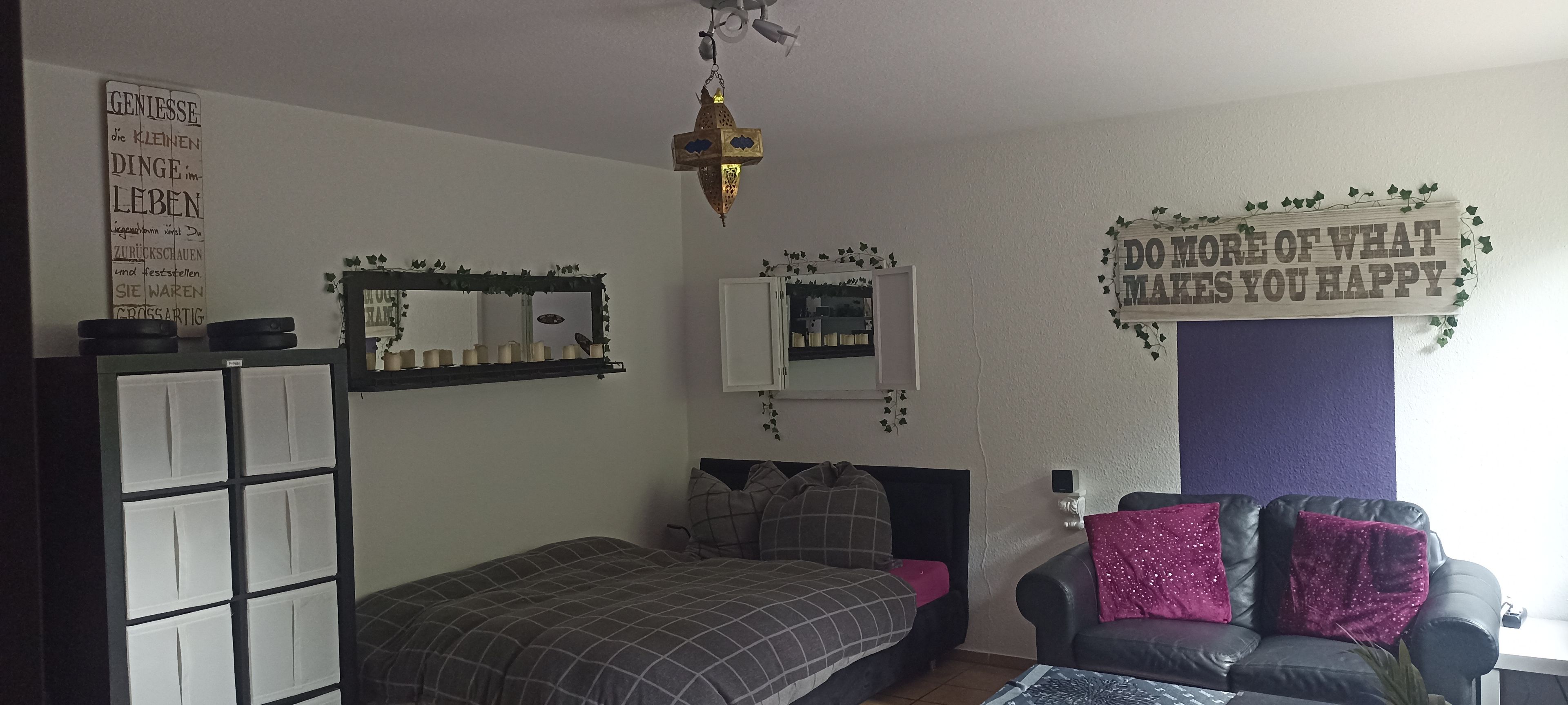Ein Schlafzimmer mit einem Bett, einem Sofa, einem Spiegel und einer Wanddekoration.