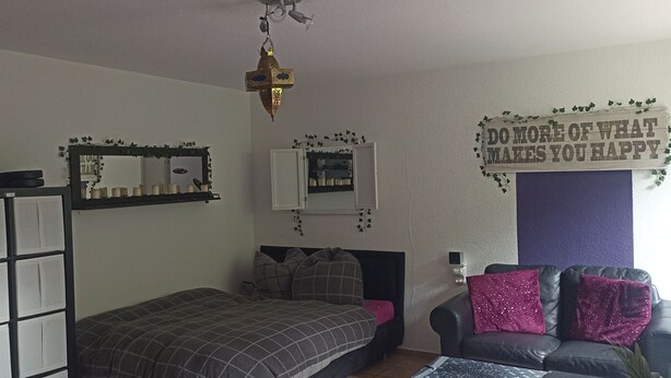 A bedroom with a bed, a sofa, a mirror, and a wall decoration. - Phil's Cozy Apartment: Self-Check-In Near the Airport, Free Parking, Airport Bus Stop (Leinfelden-Echterdingen)