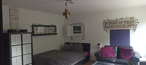 Ein Schlafzimmer mit einem Bett, einem Sofa, einem Spiegel und einer Wanddekoration.