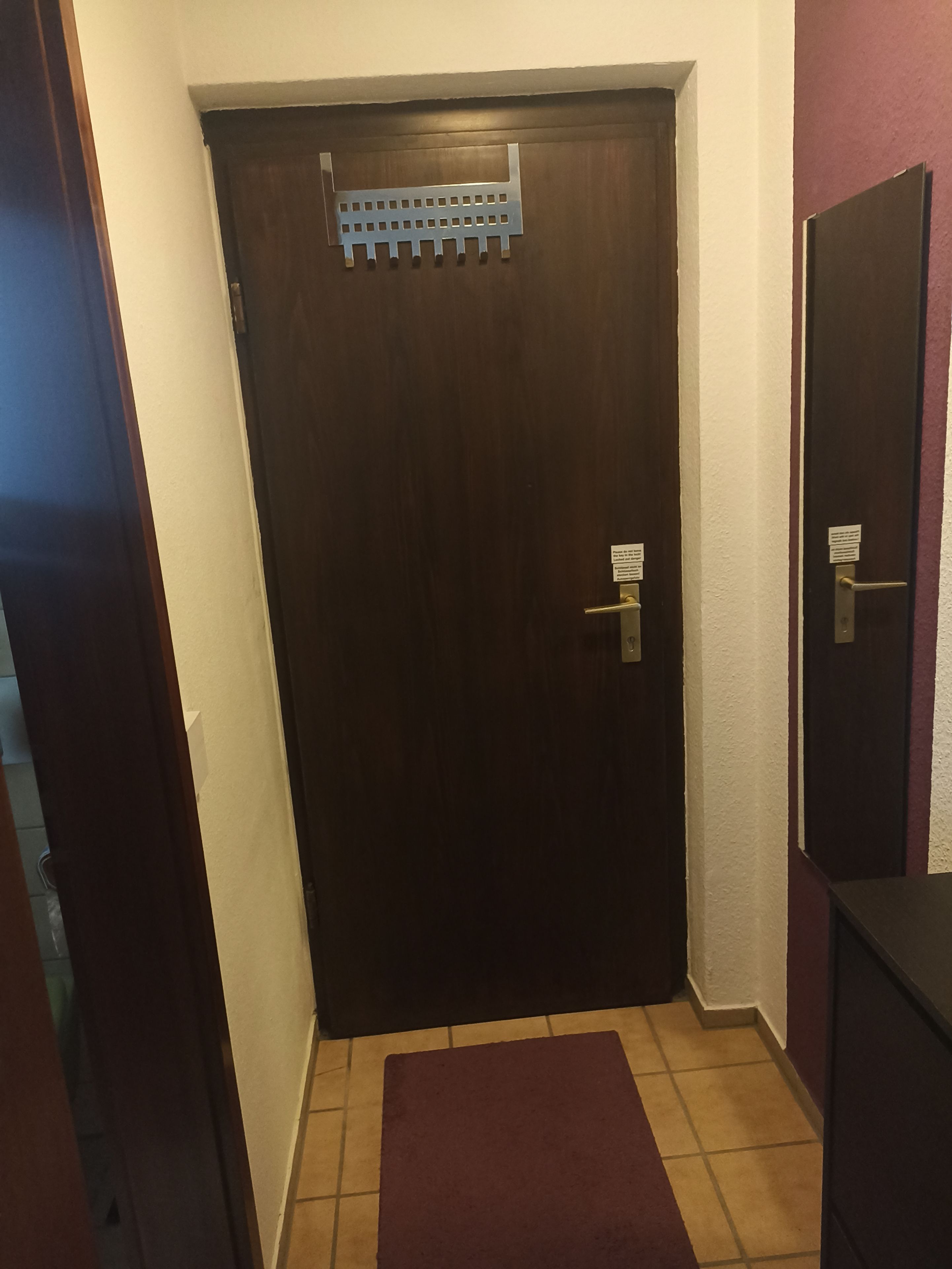 A dark wooden door with a metal handle and a small sign above it.