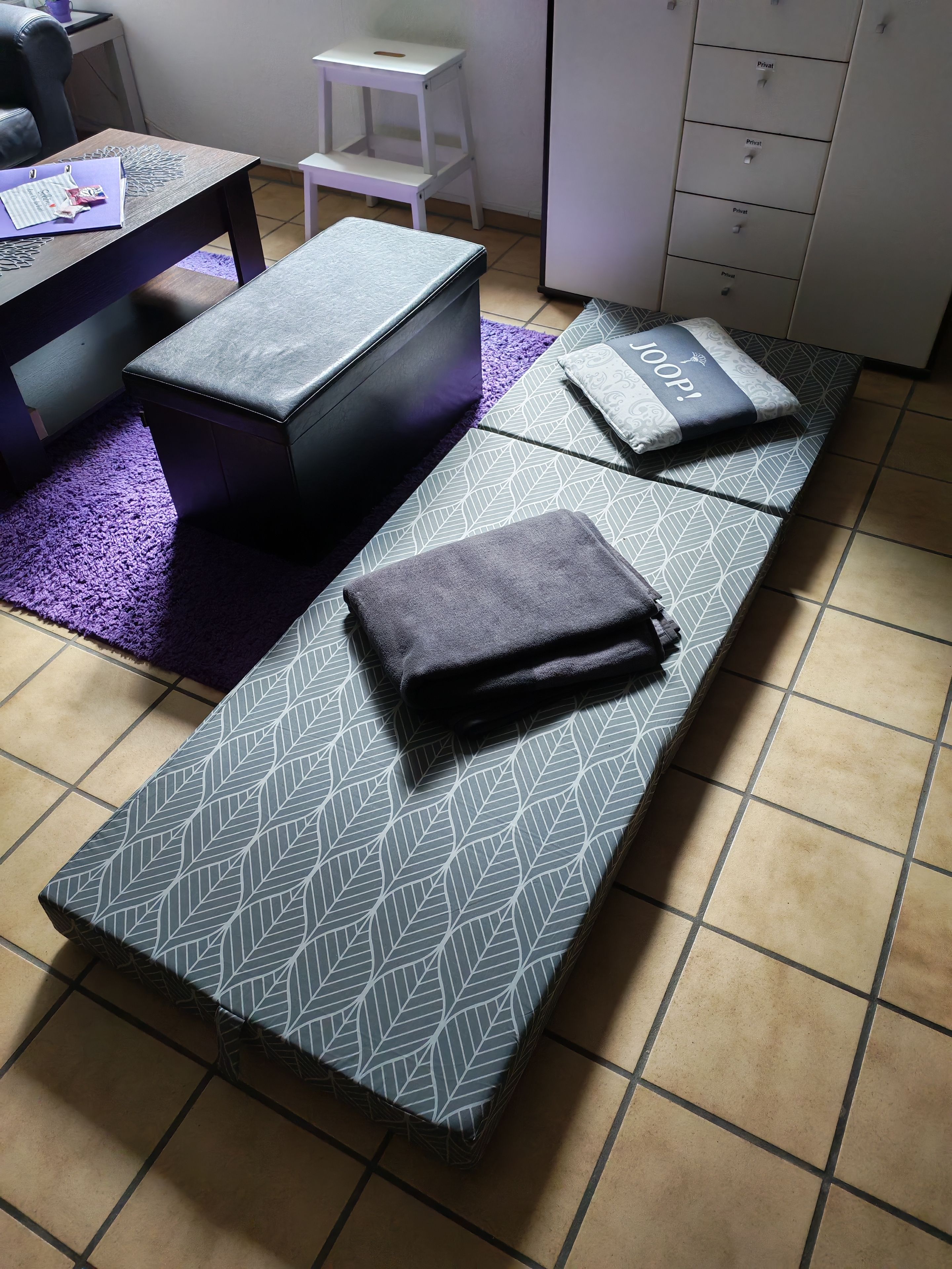 Ein Zimmer mit einem Bett, einem kleinen Tisch, einem Sessel und einem Schrank.