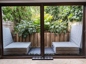 Eine Terrasse mit zwei gemusterten Stühlen, einem Holzzaun und üppiger Bepflanzung.