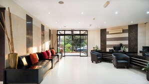 A reception area with a sofa, chairs, a desk, and a view of greenery outside. - Hotel 33 Kampala (Kampala)