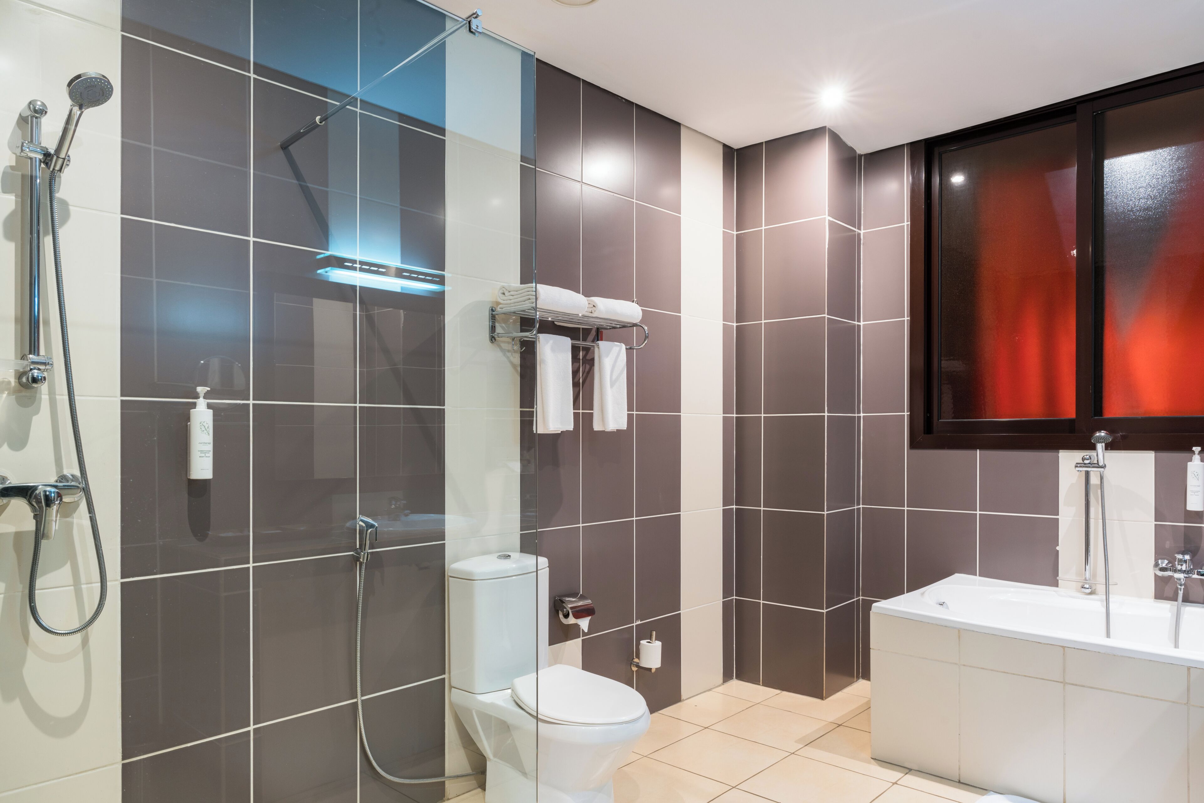 Un baño moderno con cabina de ducha de vidrio, inodoro blanco y bañera blanca.
