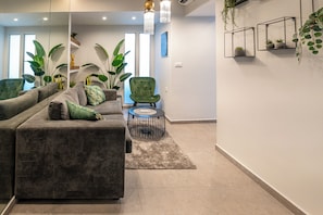 Ein modernes Wohnzimmer mit einem grauen Sofa, einem grünen Sessel und einem kleinen runden Tisch.