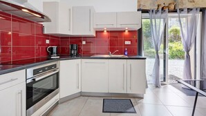 A modern kitchen with a built-in oven, a coffee maker, and a sink. - Gîte Du Côteau – 10 min from Puy du Fou (Les Herbiers)