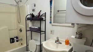 Een badkamer met een badkuip, toilet, wastafel en een wasmachine.
