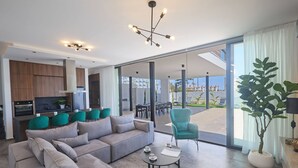 A modern living room with a sofa, coffee table, and a view of the outdoors. - Brand New 4 Bedroom Villa in Protaras Center (Paralimni)