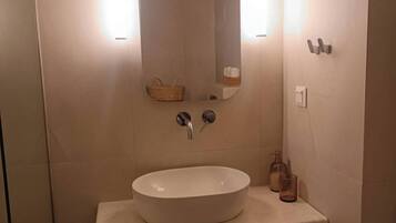A bathroom with a white sink, wooden vanity, a mirror, and two wall-mounted lights.