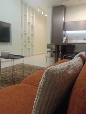 Un salon avec un canapé, une table basse et un téléviseur fixé au mur.