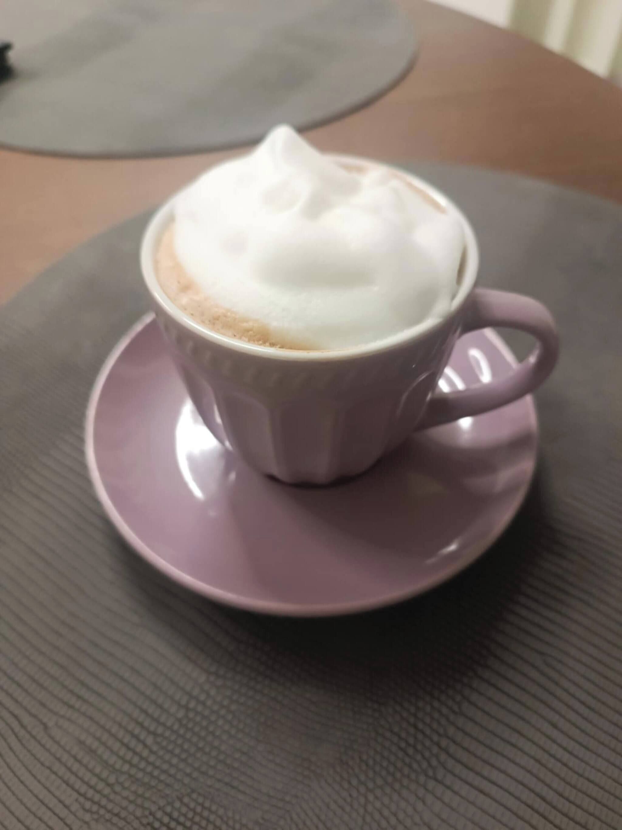 A cup of coffee with foam on a saucer.