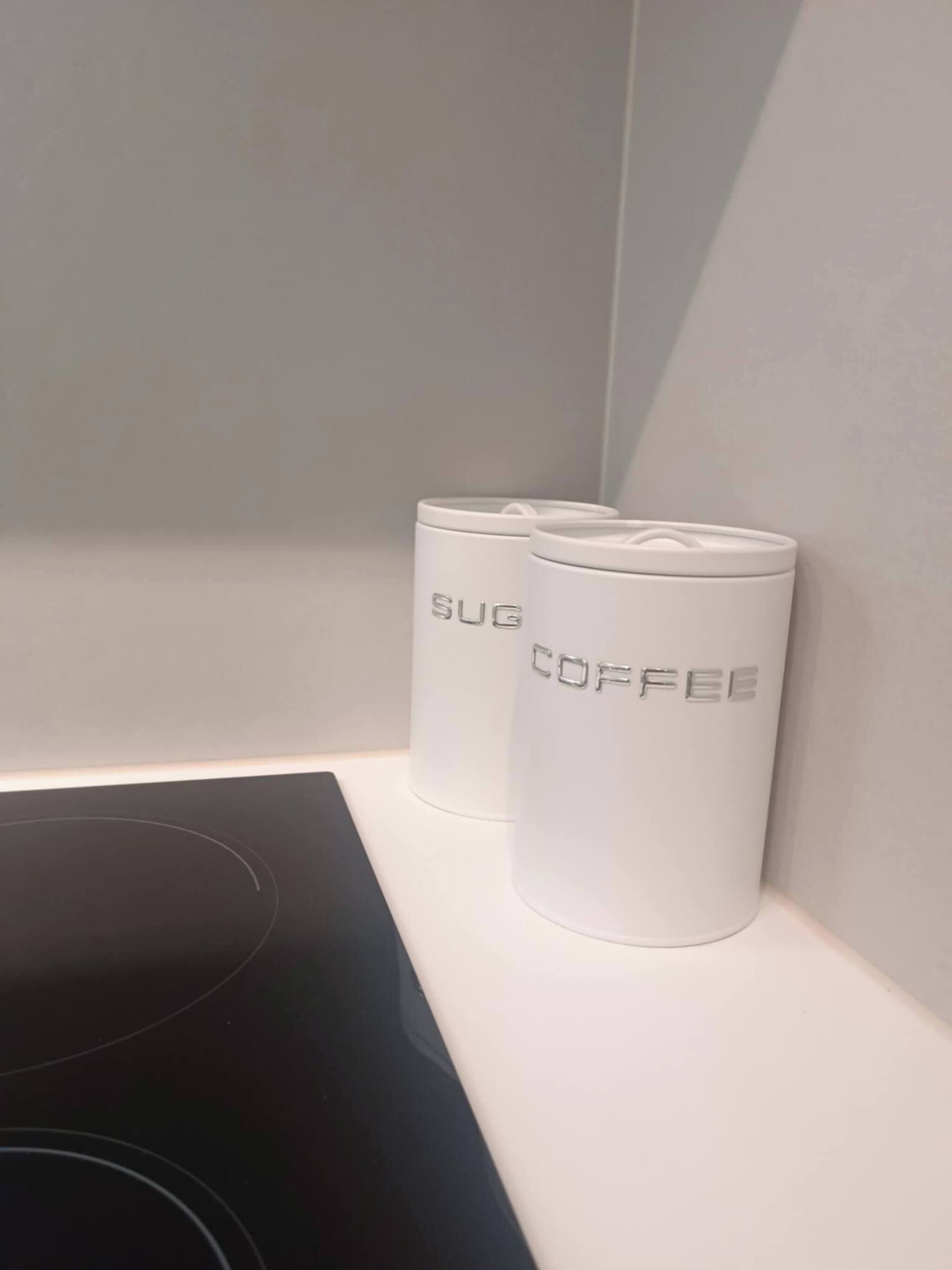 Two white cylindrical containers with embossed text on a white surface.