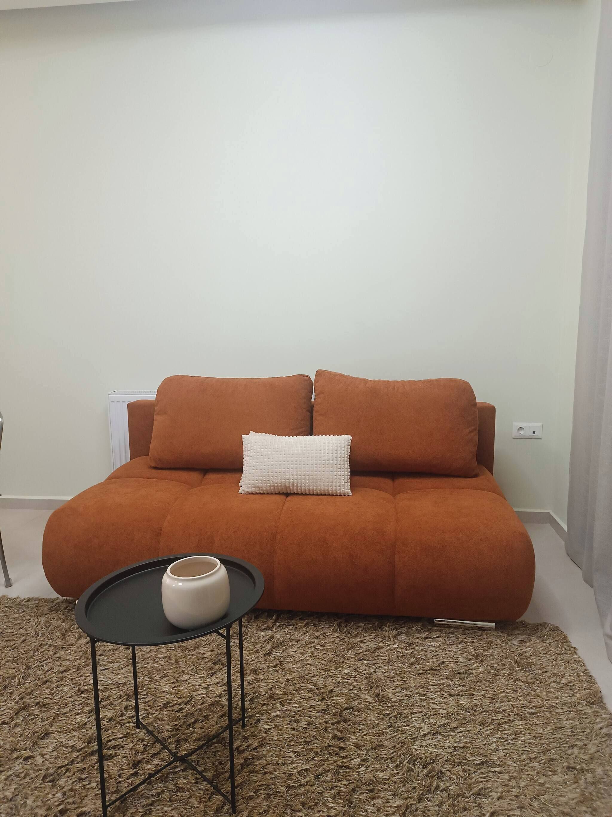 A living room with a sofa, a small round table, and a rug.