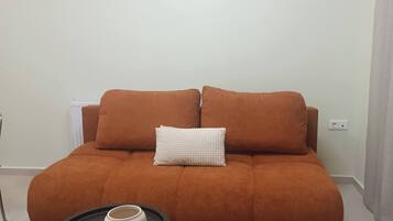 A living room with a sofa, a small round table, and a rug.