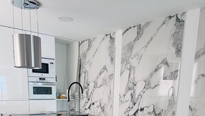 Cocina moderna con salpicadero de mármol, electrodomésticos de acero inoxidable y una isla central con encimera de mármol negro.
