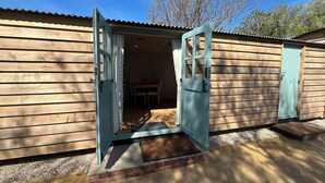 A wooden building with an open door leading to an interior space. - The Orchard (Dorchester)