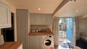 A compact kitchen with a washing machine, wooden countertop, and a view to the outside.