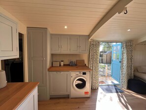 Cocina compacta con lavadora, encimera de madera y vistas al exterior.