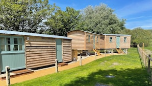 A row of wooden mobile homes with a grassy yard and a wooden fence. - The Orchard (Dorchester)