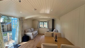 A cozy room with a wooden floor, a sofa, a dining table with chairs, and a window with curtains.
