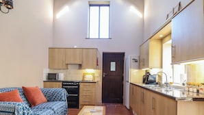 Um espaço compacto com cozinha compacta, sofá e mesa pequena.
