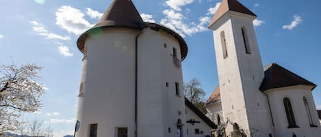 Una iglesia con un campanario y una torre redonda, rodeada de césped.