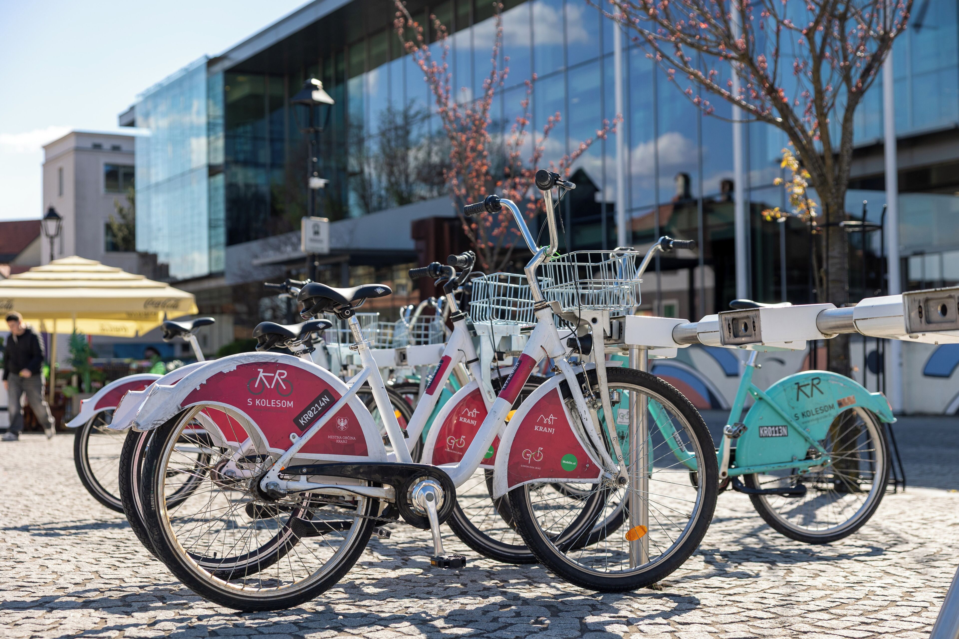 Varias bicicletas con cestas aparcadas sobre adoquines.