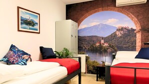 A room with two beds, a radiator, a plant, a cabinet, and a mural of a bridge over a lake. - Old Town Guest Accommodation (Kranj)