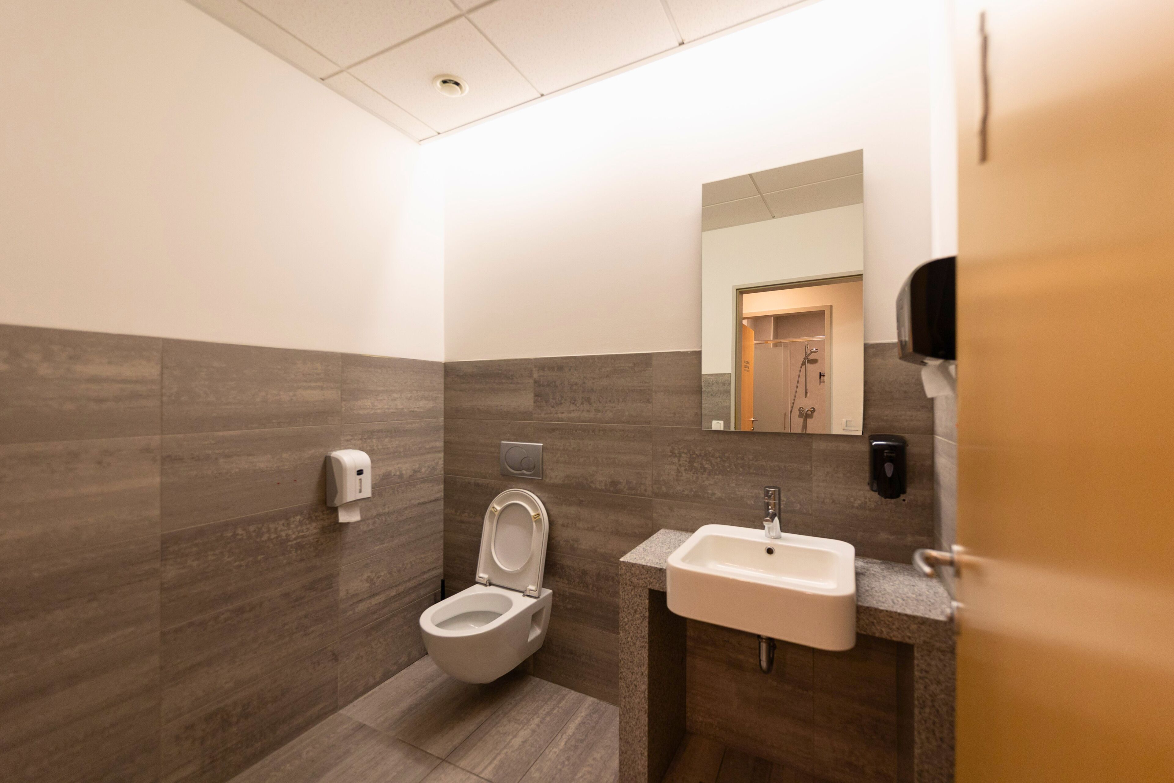 A modern bathroom with a toilet, sink, and hand dryer.