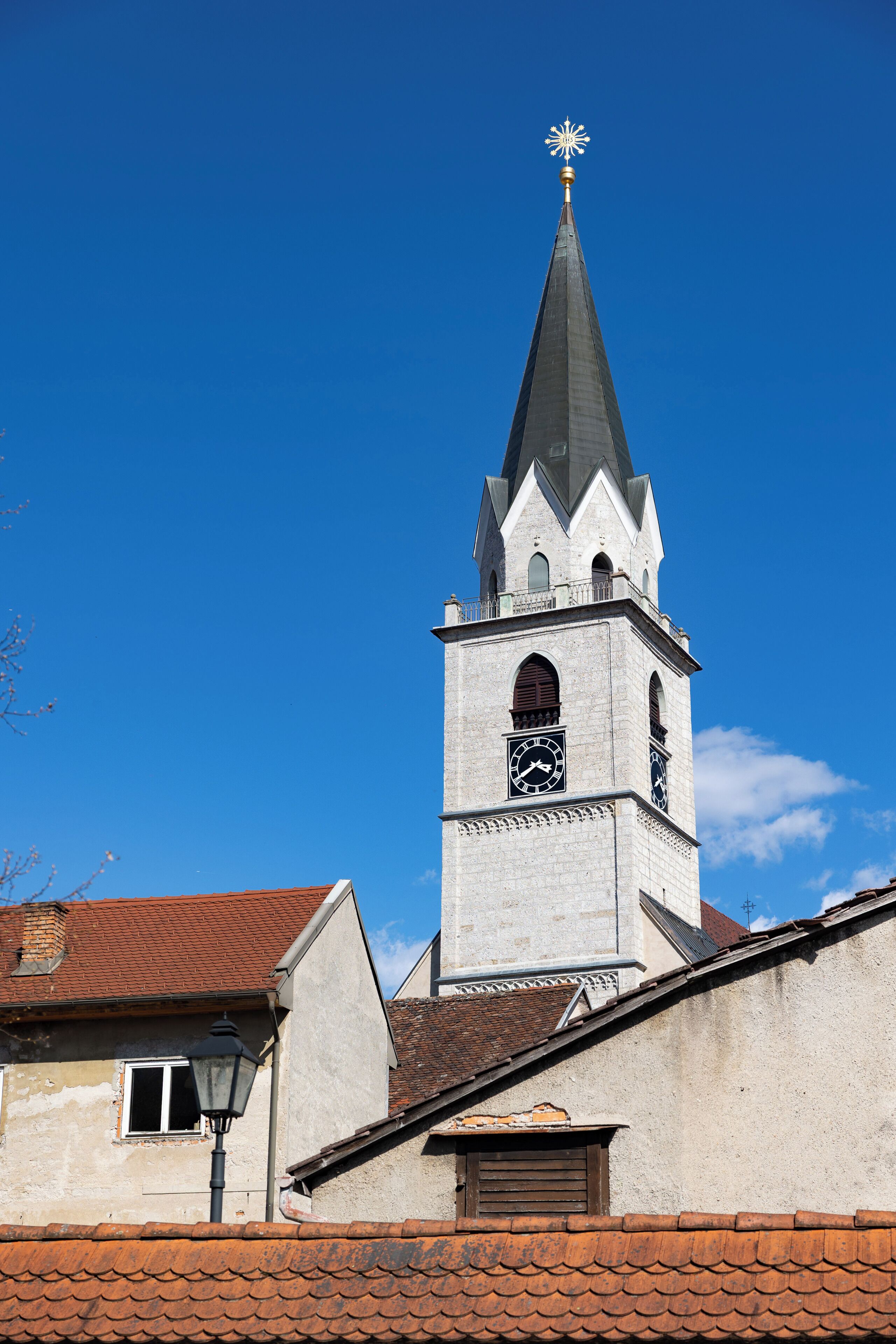 A church with a pointed steeple, a clock, and a weather vane.