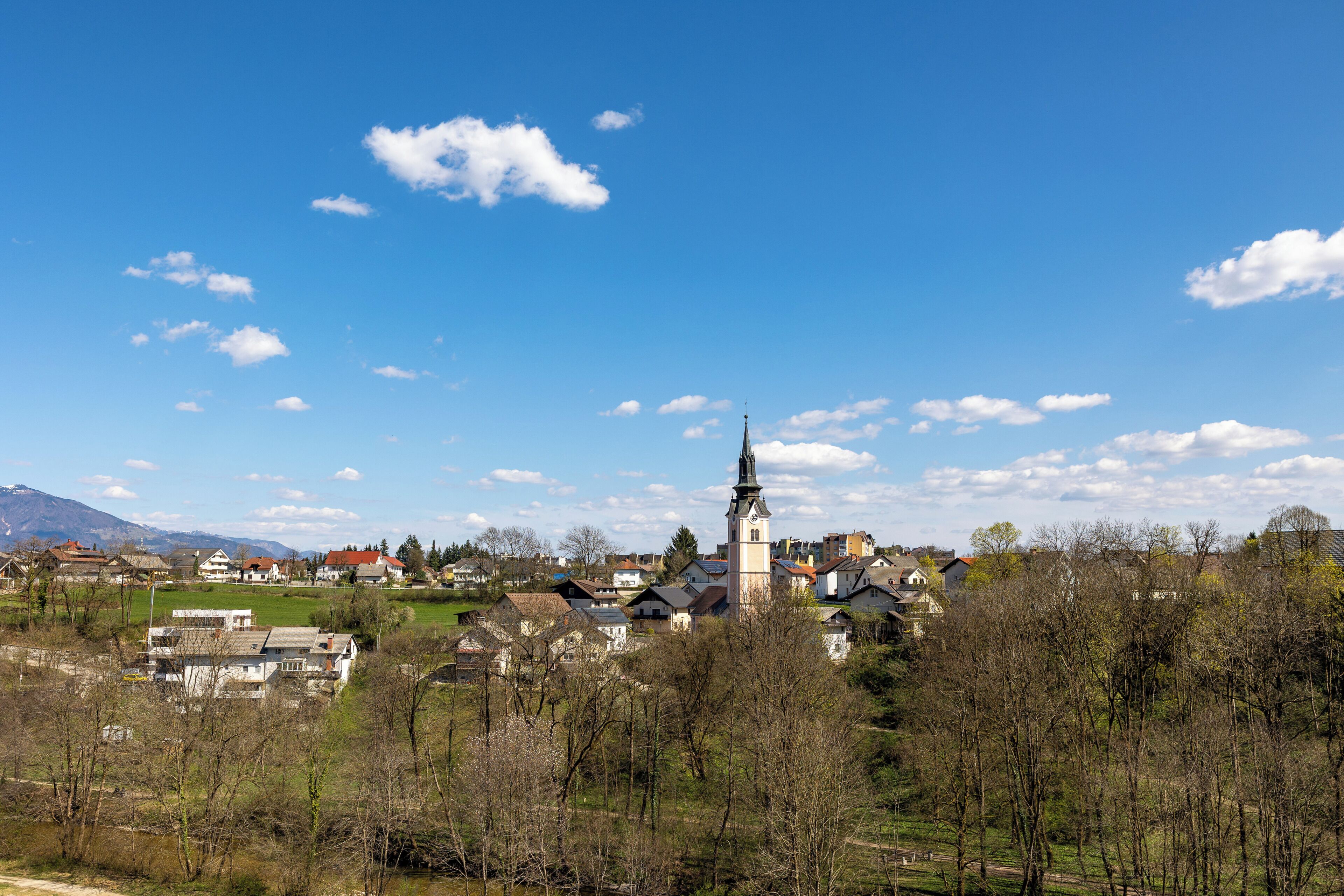 A town with a prominent church tower, surrounded by residential buildings and a clear sky.