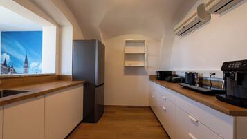 Una cocina compacta con refrigerador, microondas, cafetera y ventana con vista a la ciudad.