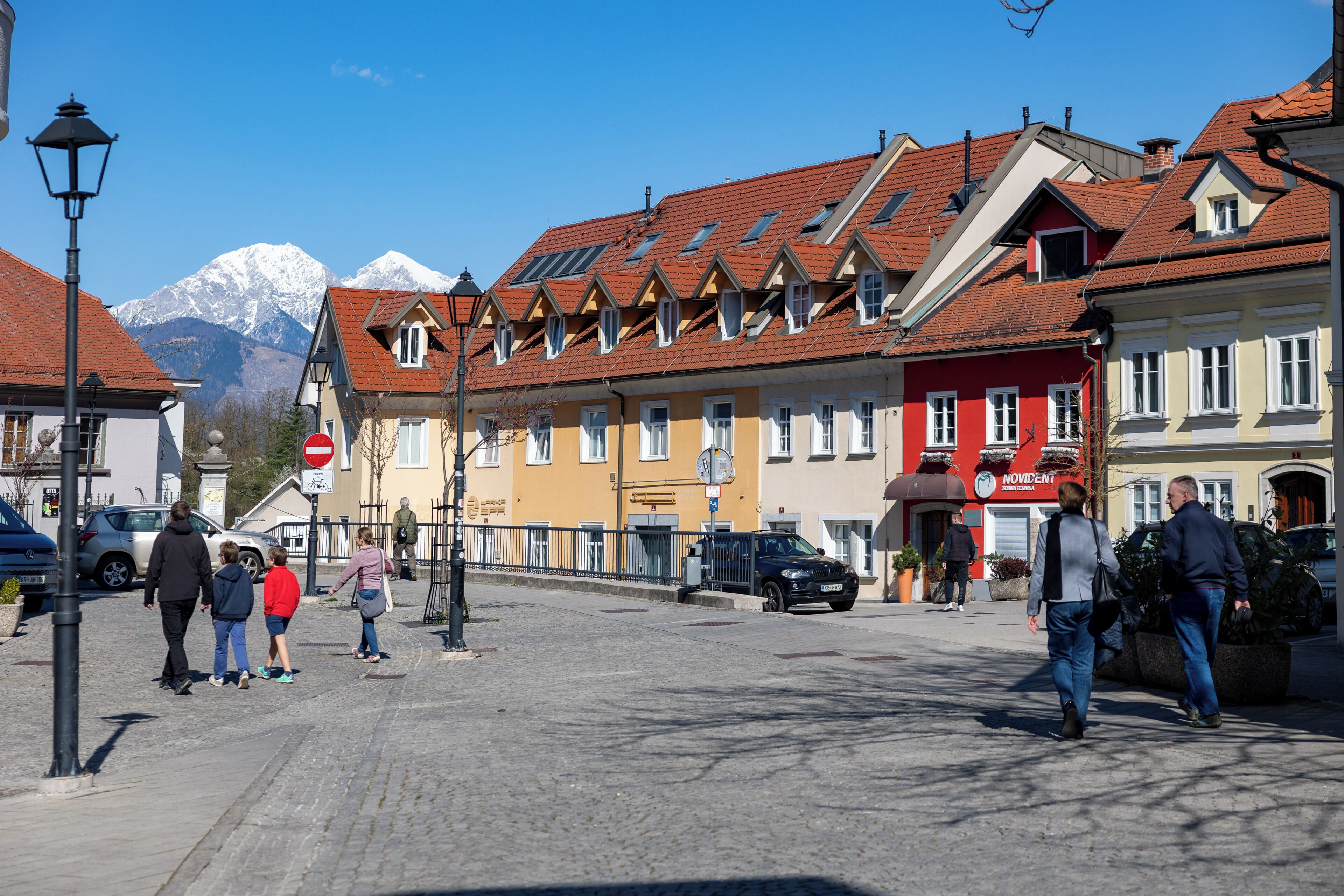 A cobblestone street with buildings, a stop sign, and a mountain in the background.