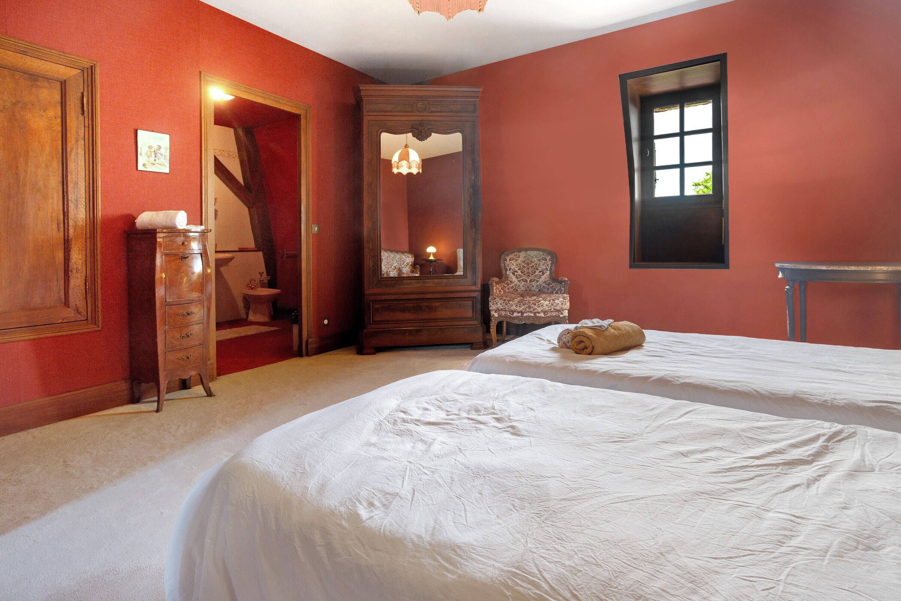 Une chambre avec deux lits, une commode, une chaise, un miroir et une fenêtre.