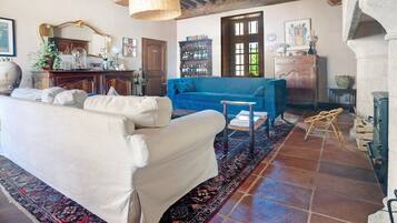 A living room with a white sofa, a blue sofa, a wooden coffee table, a patterned rug, a bookshelf, and a large mirror.