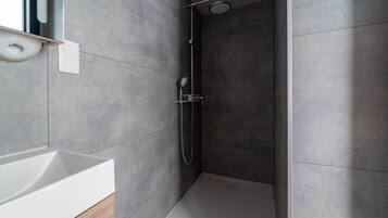Un bagno moderno con una vasca, una doccia con soffione a mano e un water.