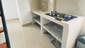 A compact kitchen with a sink, a stove, and a small countertop. - Cozzy Aesthetic Guest House (Ubud)
