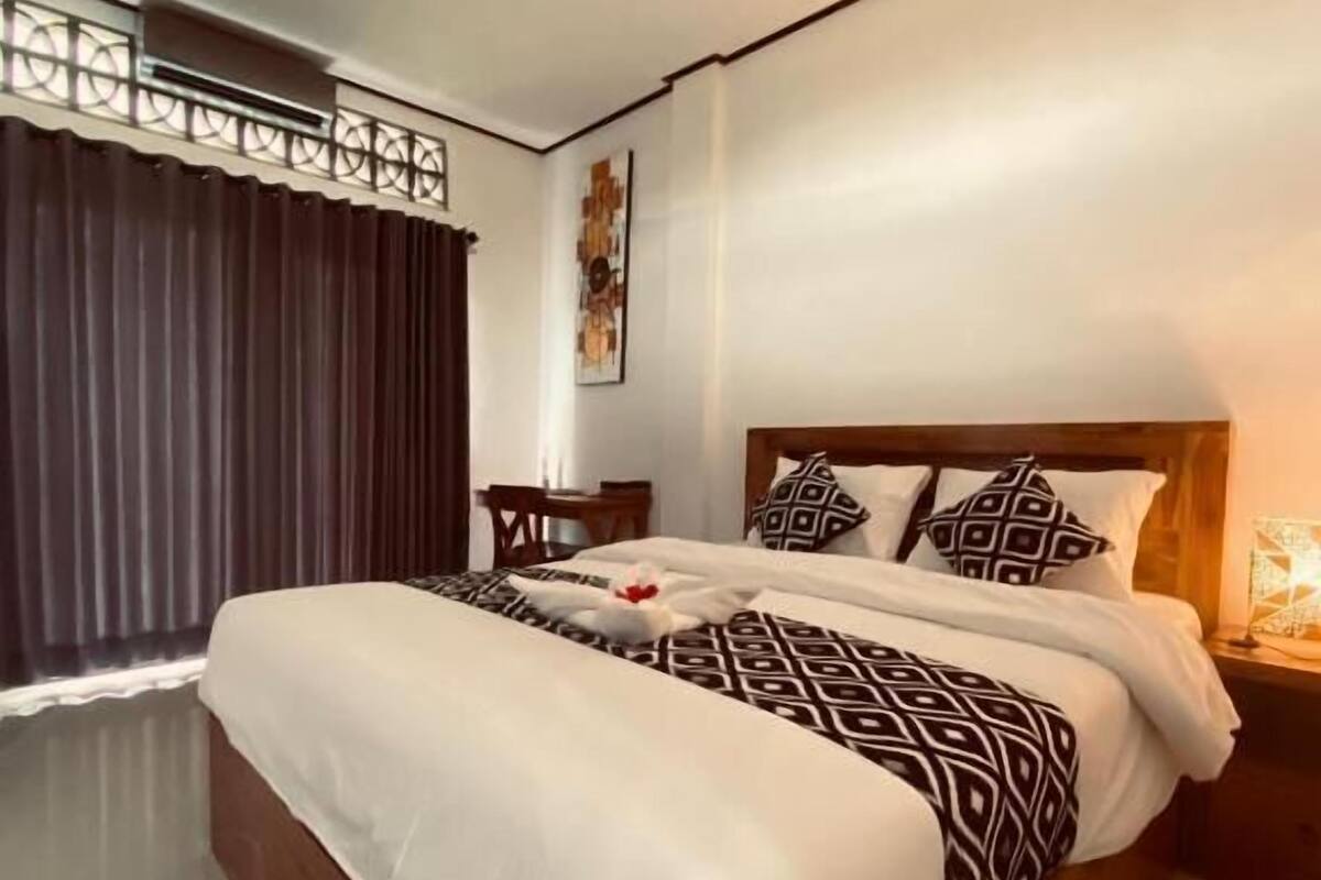 Una habitación de hotel con una cama grande, una mesita pequeña y un adorno en la pared.