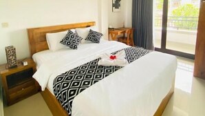 A hotel room with a bed, a nightstand, a chair, a window with a view, and a decorative wall piece. - Cozzy Aesthetic Guest House (Ubud)