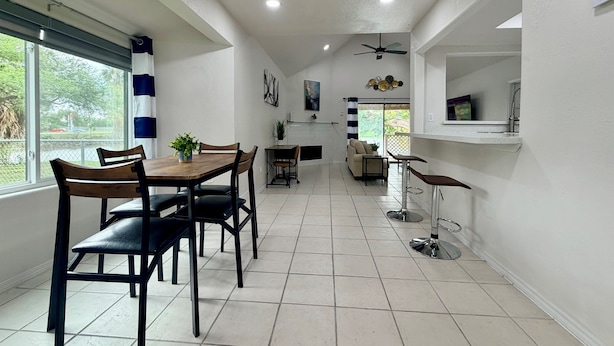 A modern kitchen with a dining area, a ceiling fan, and a view through the window. - Waterside at VICC - Cozy, Blissful Views! (Brownsville)