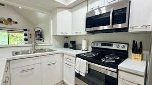A modern kitchen with white cabinetry, stainless steel appliances, and a gas stove. - Waterside at VICC - Cozy, Blissful Views! (Brownsville)