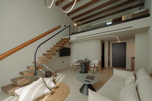 A modern living space with a wooden staircase, a dining area with chairs, a sofa, and a round coffee table. - Superior Villa - Kyklio Pavilions Nafplio (Nafplio)