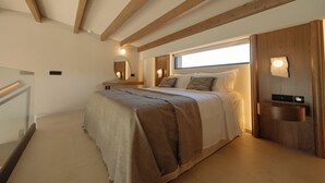 Un dormitorio con una cama grande, vigas de madera, una ventana, una mesita de noche y un espejo.